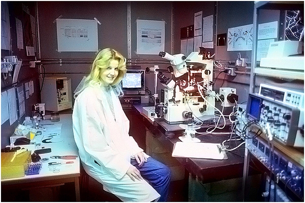 图为我的妻子与一台奥林巴斯倒置显微镜的合影。1985 年前后，我就是用这台显微镜在阿尔伯塔大学观测记录无脊椎动物脑细胞发出的电信号。这台显微镜配有一台奥林巴斯 OM-4 35mm 的单反相机机身，以及一台可以制作低速影片的弱光摄像机。【编辑吐槽：看照片完全不觉得显微镜是构图的核心……】