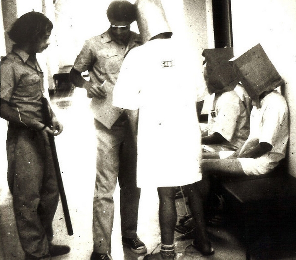 津巴多教授设计的“斯坦福监狱实验”：在实验中，扮演“狱警”的大学生（左一、左二为其中的两人）在极短的时间里转变成了虐待狂，拒绝向扮演“囚犯”的学生（图中戴头罩者为其中三人）提供水和食物、不让他们睡觉、用灭火器喷“囚犯”并使他们光着身子遭受鞭打（Dr. Philip Zimbardo/nytimes.com）