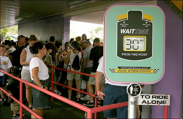 在迪斯尼乐园排队等候的游客，通道弯弯曲曲，沿途还设有显示屏显示等候时间。（图片：mousecomedy.com）